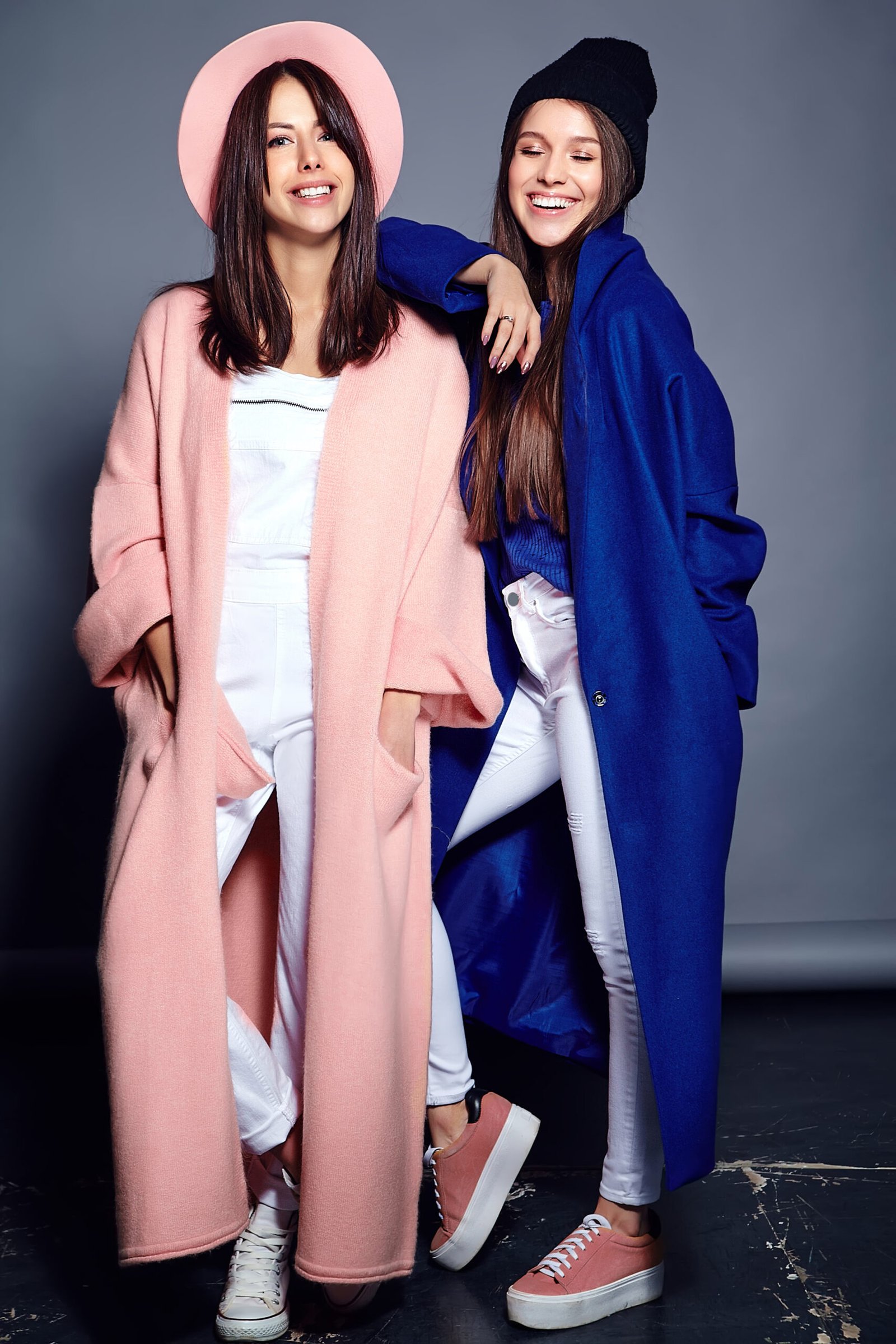 fashion portrait of two smiling brunette women models in summer casual hipster overcoat posing on gray background. full length